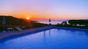 A swimming pool with a sunset view, lounge chairs, and an umbrella. - Hôtel Céline (Coti-Chiavari)