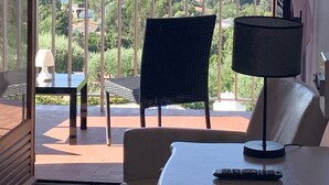 A balcony with a view of the sea and hills, a table, two chairs, and a lamp. - Hôtel Céline (Coti-Chiavari)