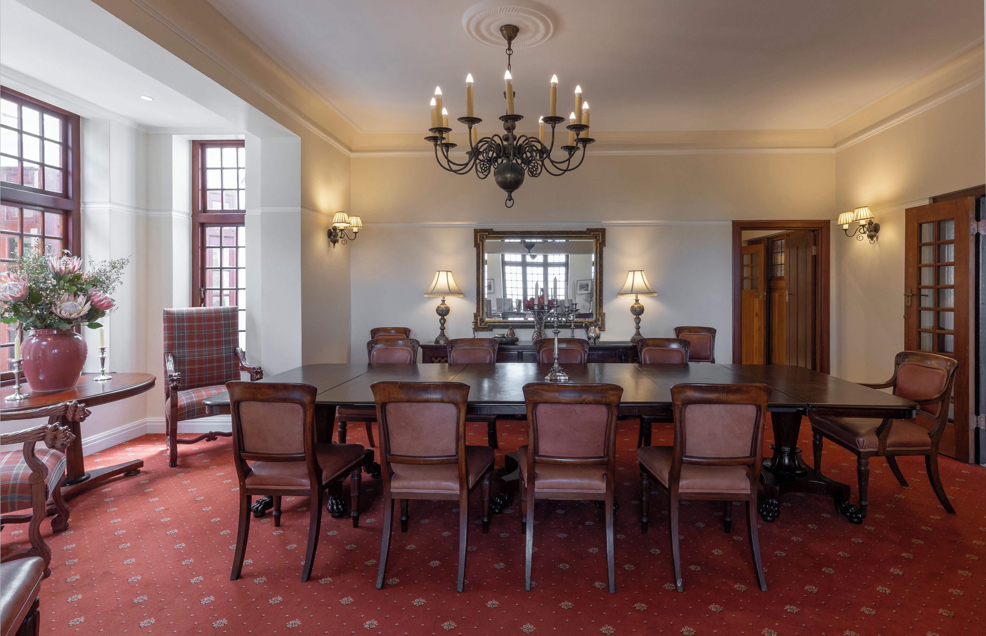 A formal dining room with a large table, multiple chairs, a chandelier, and a large mirror.