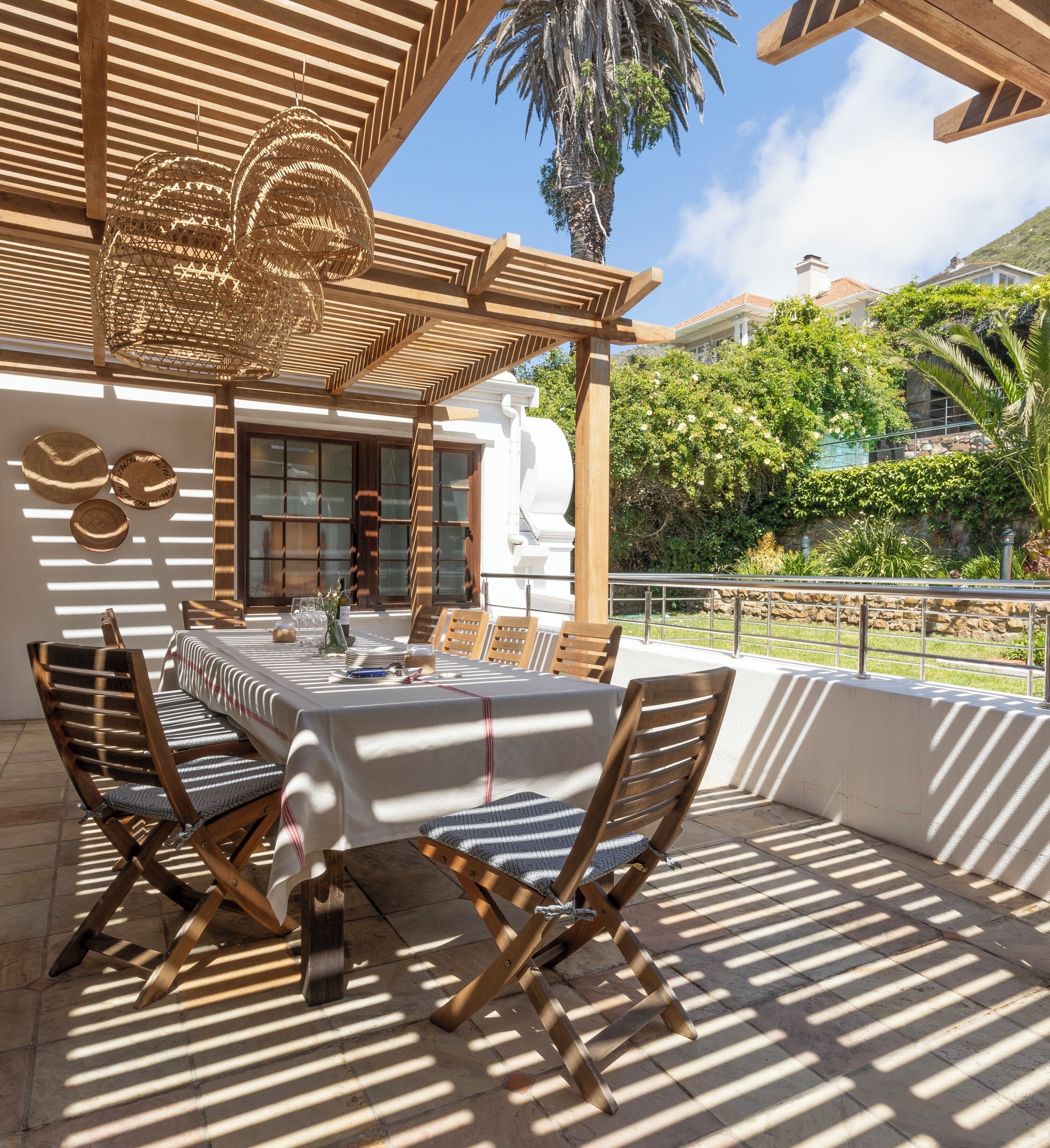 An outdoor dining area with a pergola, wooden chairs, and a table set for four.