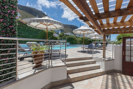 Una piscina al aire libre, sombrillas, sillones reclinables de piscina