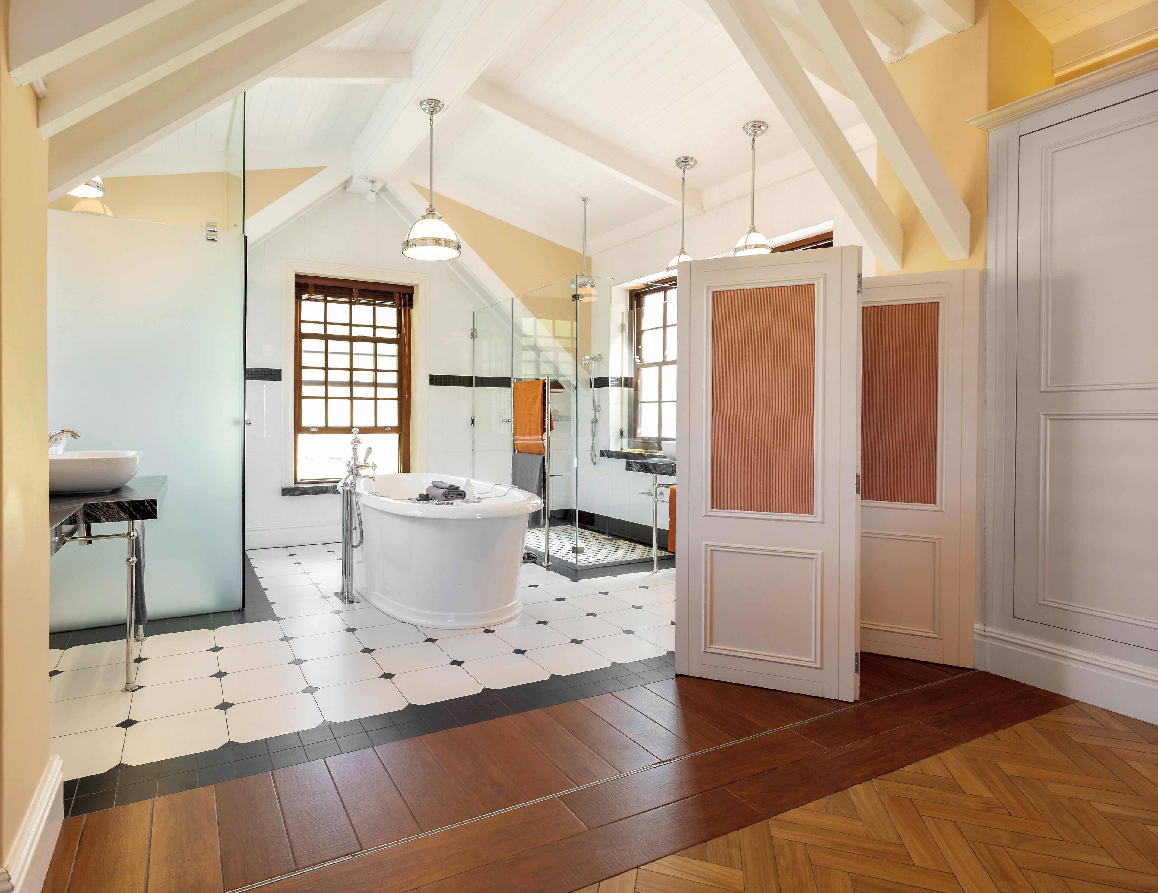 Une salle de bain spacieuse dotée d’une baignoire sur pieds, d’une douche à parois de verre et d’une grande fenêtre laissant entrer la lumière naturelle.