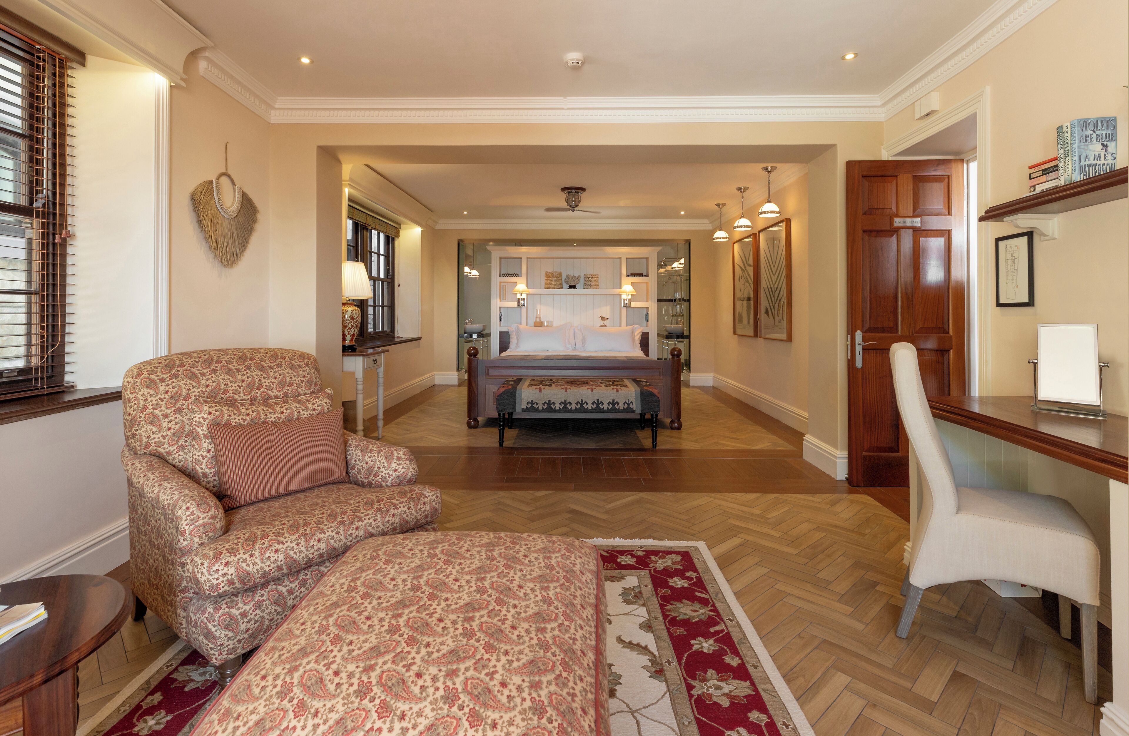 A bedroom with a large bed, a chair, a desk, and a bookshelf.