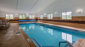 An indoor swimming pool with clear water, surrounded by lounge chairs and benches. - Best Western Hampshire Inn (Seabrook)