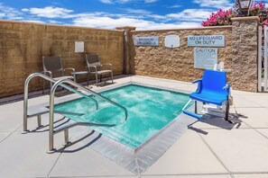 A pool area with a lifeguard chair, a blue chair, and a sign indicating a maximum spa load of 8.