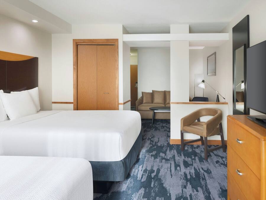 Une chambre d’hôtel avec un grand lit, un bureau, une chaise, une télévision et une armoire.