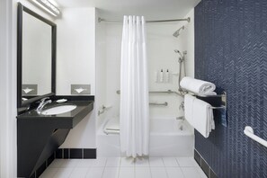 A modern bathroom with a black sink, white tiles, a shower with a white curtain, and a towel rack.