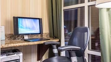A workspace with a desktop computer, a printer, and a black office chair.