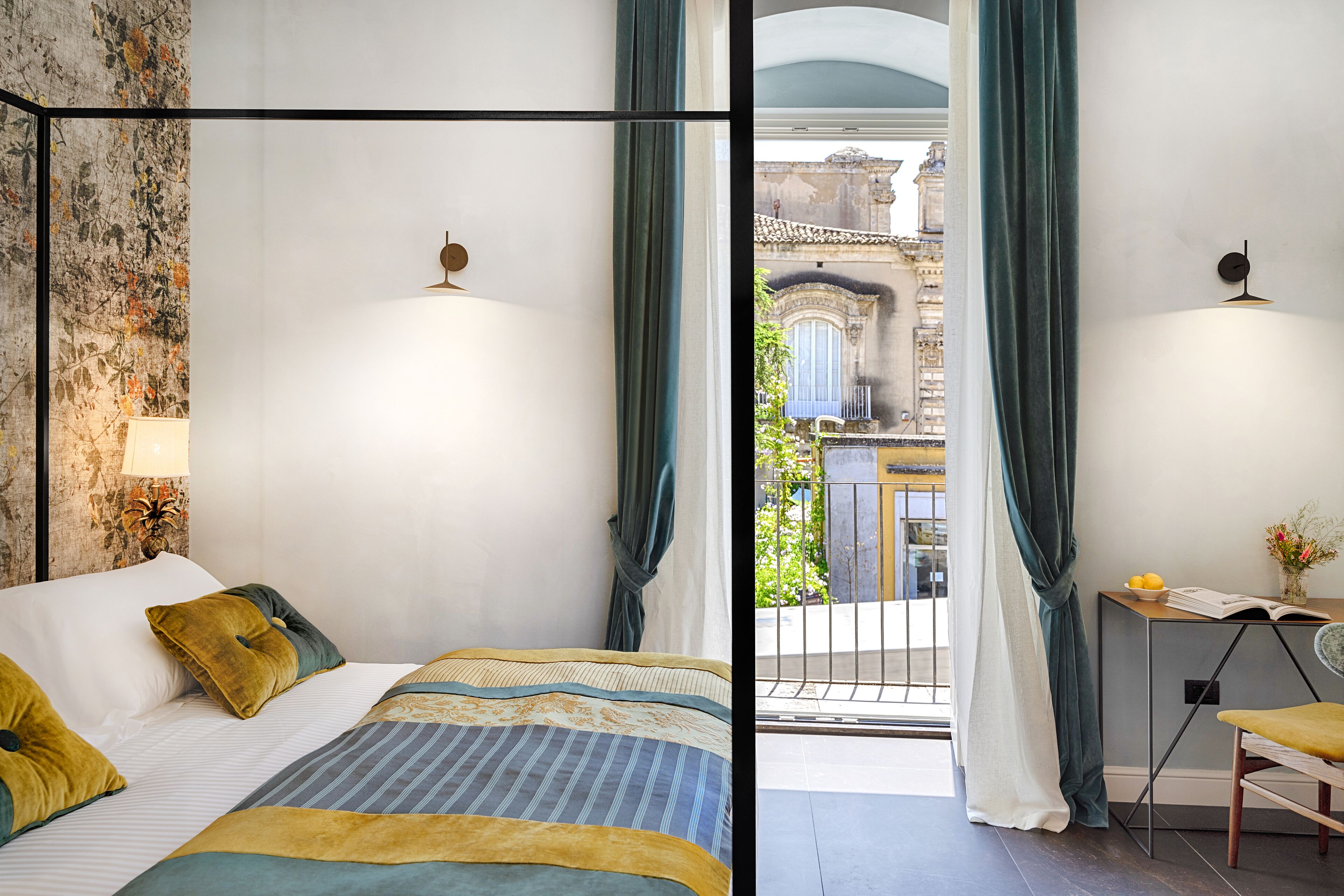A bedroom with a bed, a nightstand, a chair, and a view of the outside.