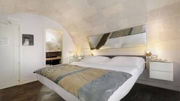 Una camera da letto con un letto grande, un comodino, uno specchio e un soffitto in pietra.