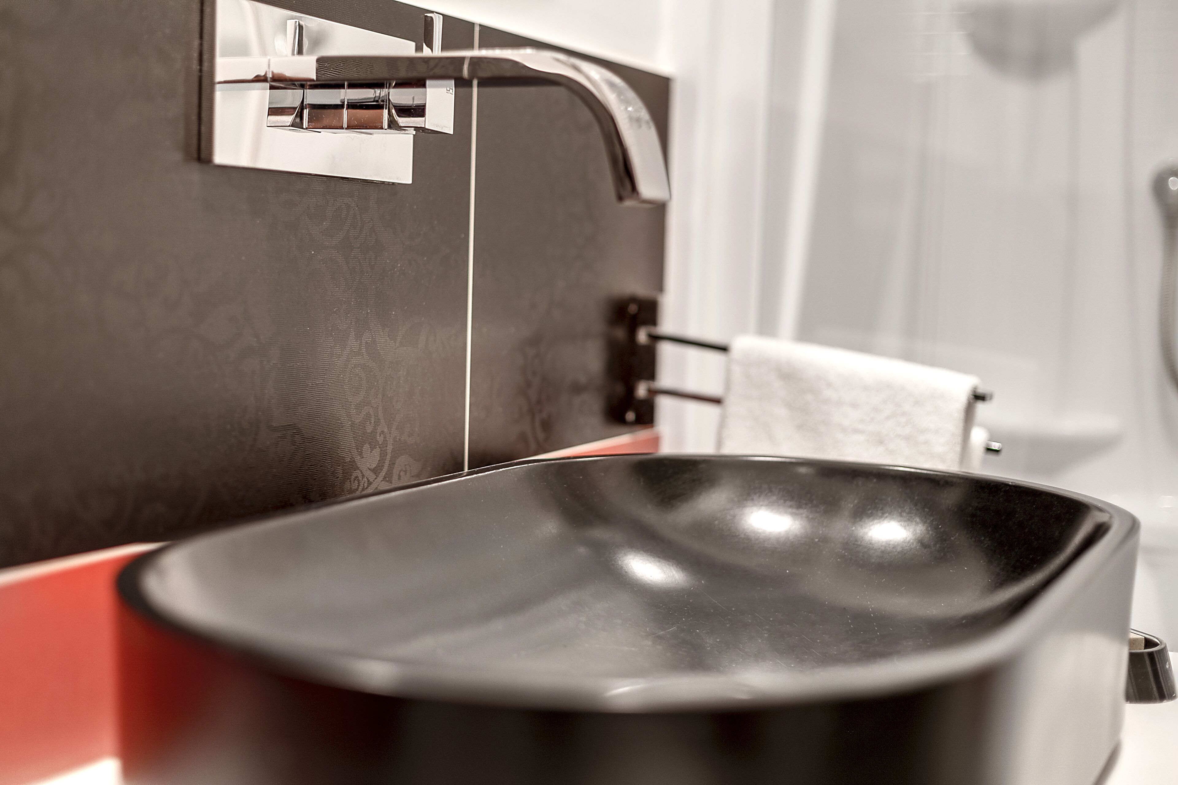 Un bagno moderno con un lavandino nero, un rubinetto cromato e un portasciugamani.