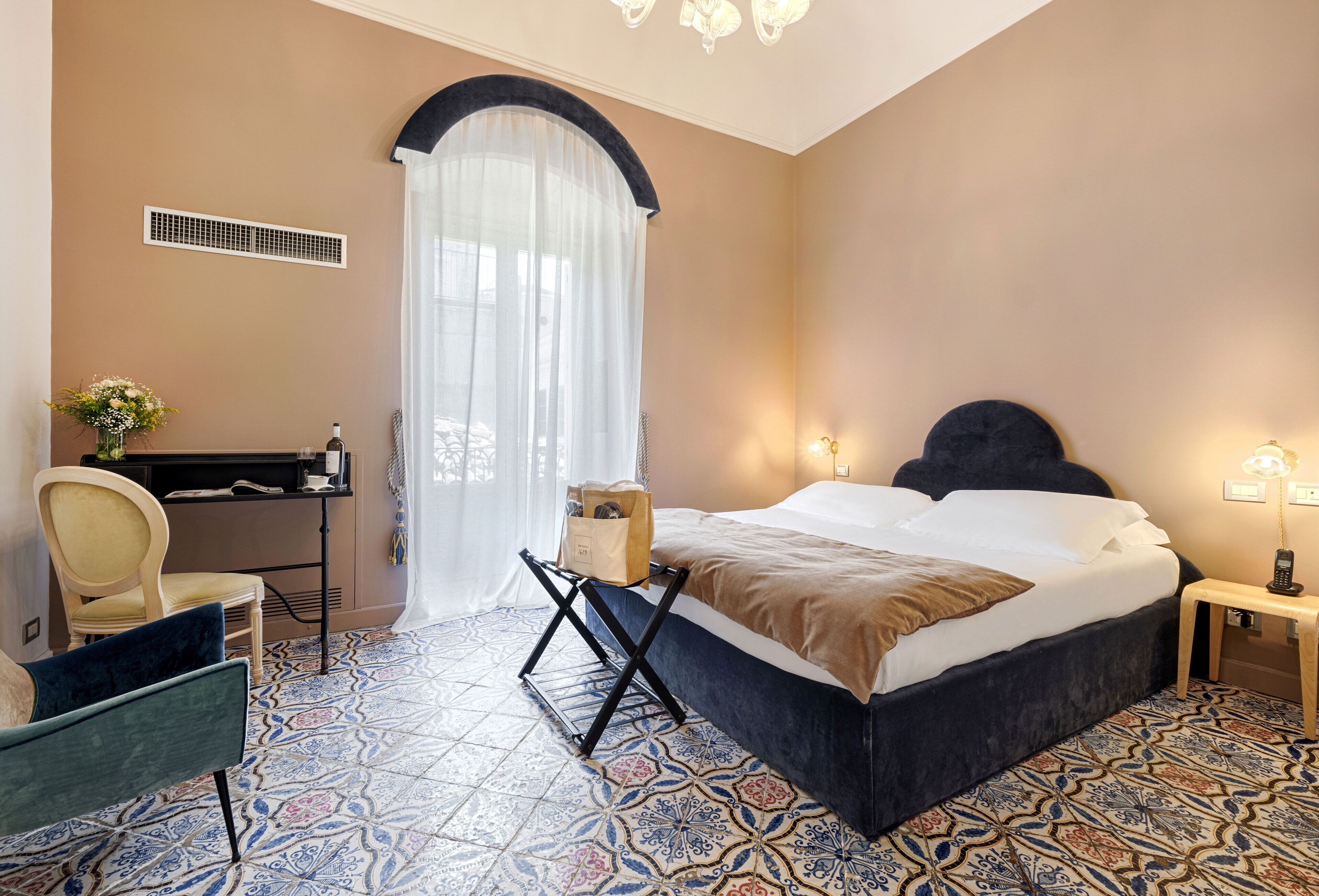 Habitación de hotel con cama, escritorio, silla y piso estampado.
