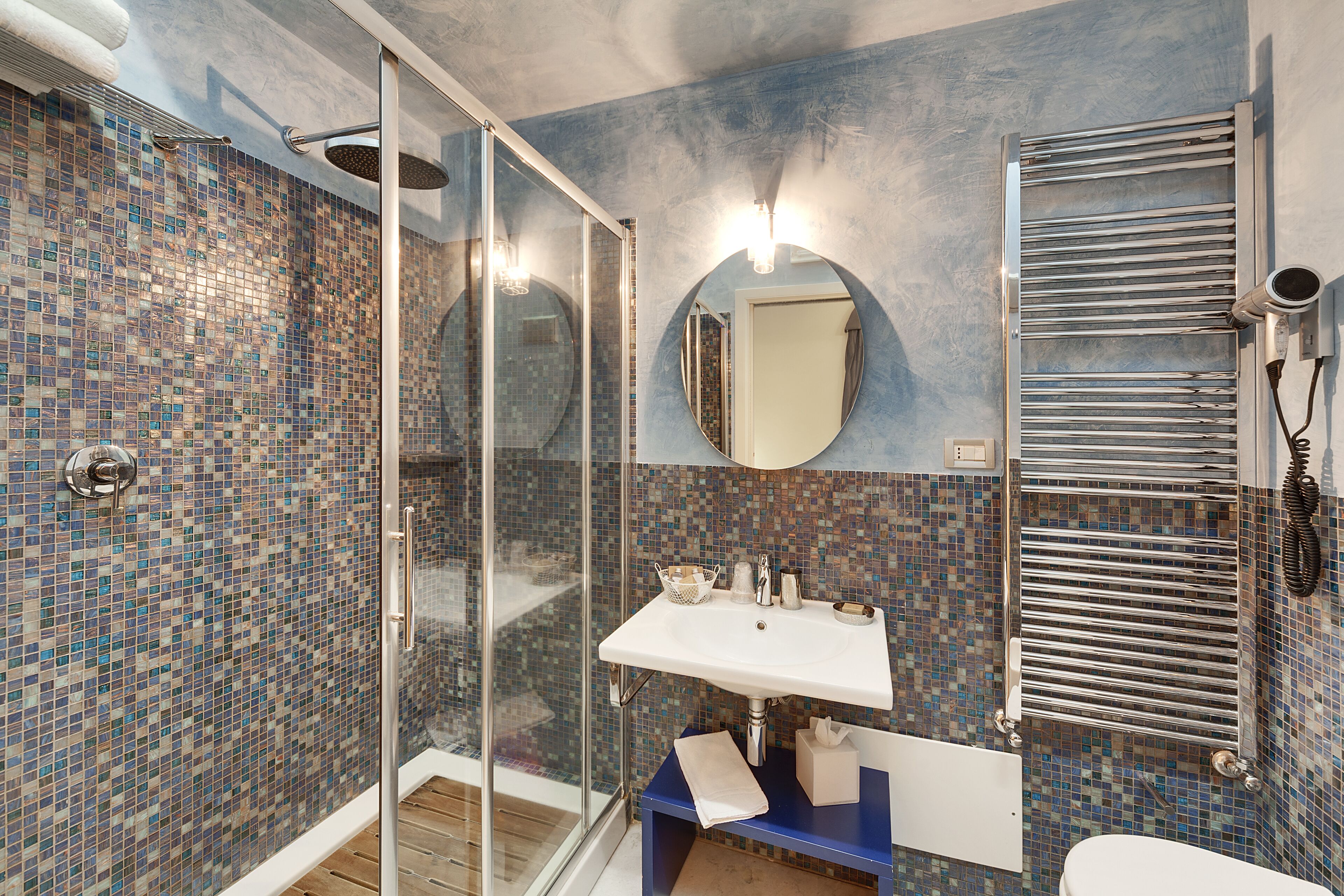 Ein Badezimmer mit Duschkabine aus Glas, Waschbecken mit Spiegel und Handtuchhalter.