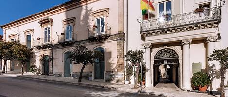 A historic building with a balcony, large windows, and a flag.