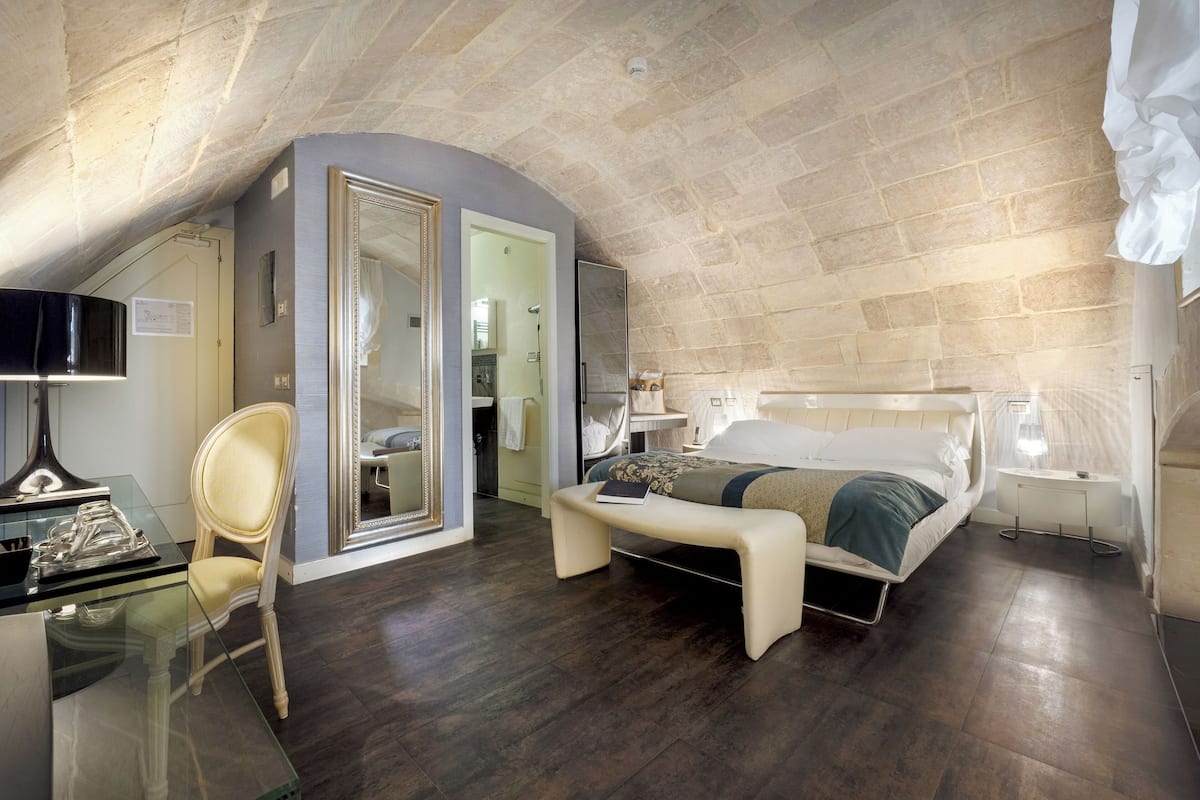 A bedroom with a bed, bedside table, chair, and a desk with a chair.
