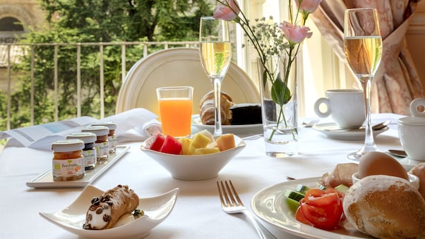 A breakfast table with a view of a historic building and a tree. - Relais Antica Badia - San Maurizio 1619 (Ragusa)