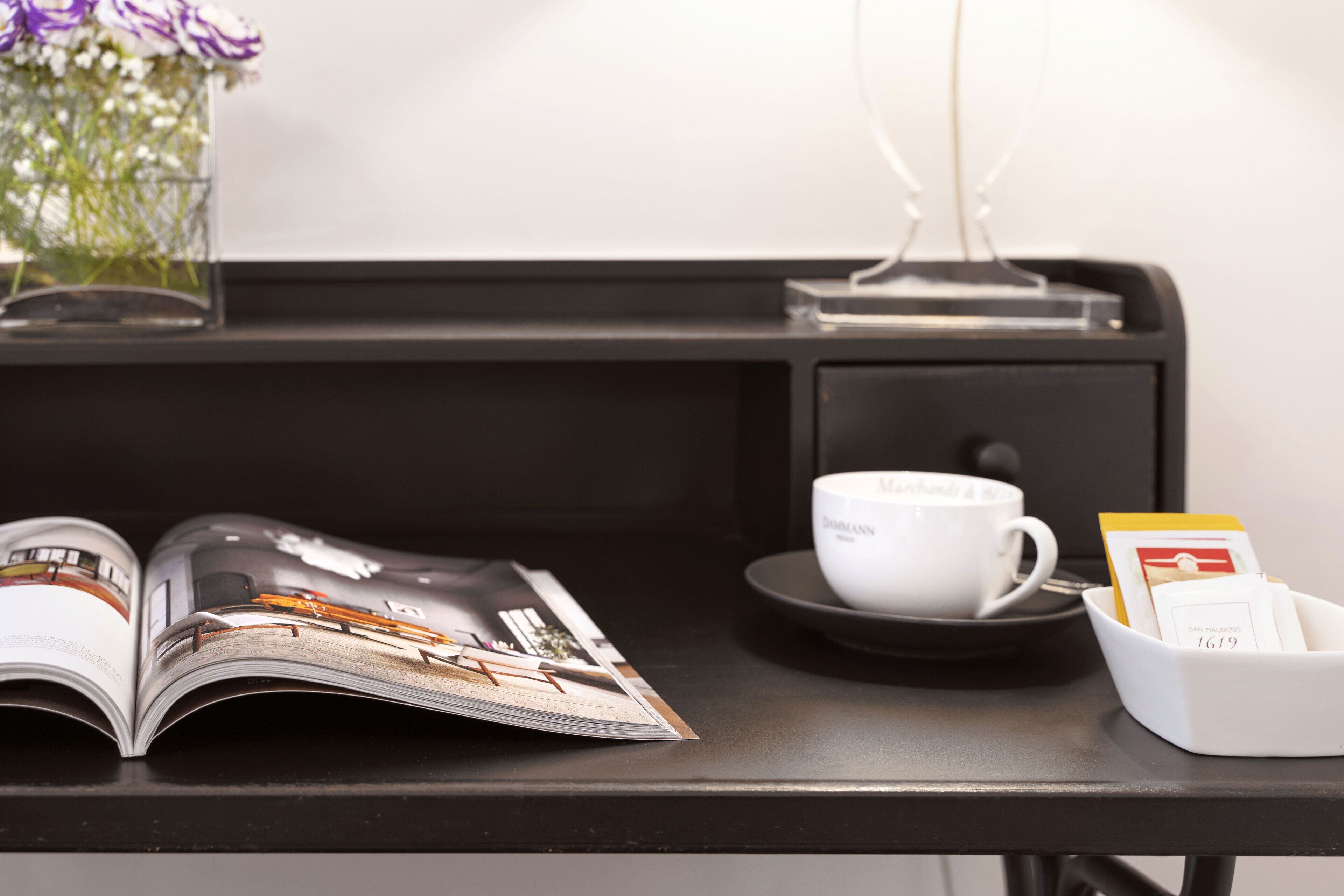 A magazine, a cup, and a tray with a card on a black table.