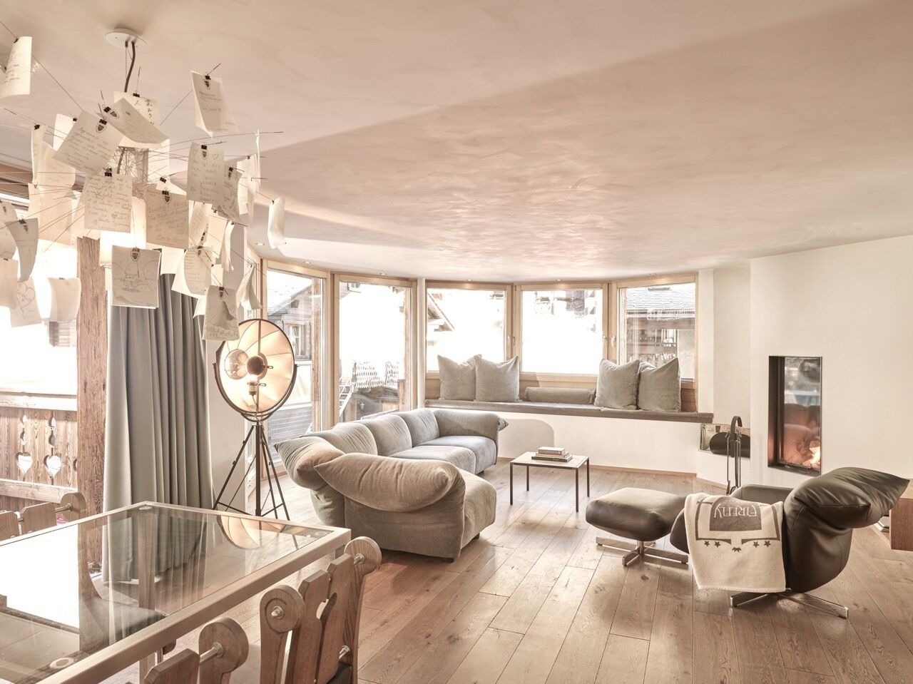 A modern living room with a glass dining table, a sofa, a chair, and a floor lamp.