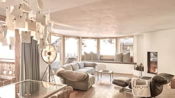 Una sala de estar moderna con una mesa de comedor de vidrio, un sofá, un sillón y una lámpara de pie.