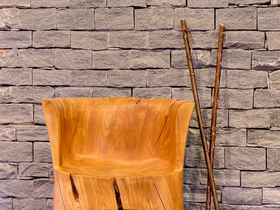 Un banco de madera junto a una pared de piedra.