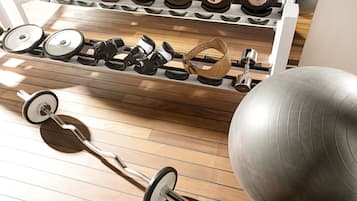 A gym with exercise equipment including dumbbells, a barbell, and a medicine ball.