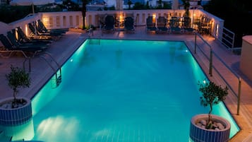 Una piscina al aire libre, sombrillas, sillones reclinables de piscina