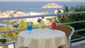 Ein Balkon mit Tisch für zwei Personen, mit Blick auf die Küste, Häuser und eine kleine Insel.