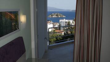 Una habitación de hotel con una cama, vistas al mar y un balcón.