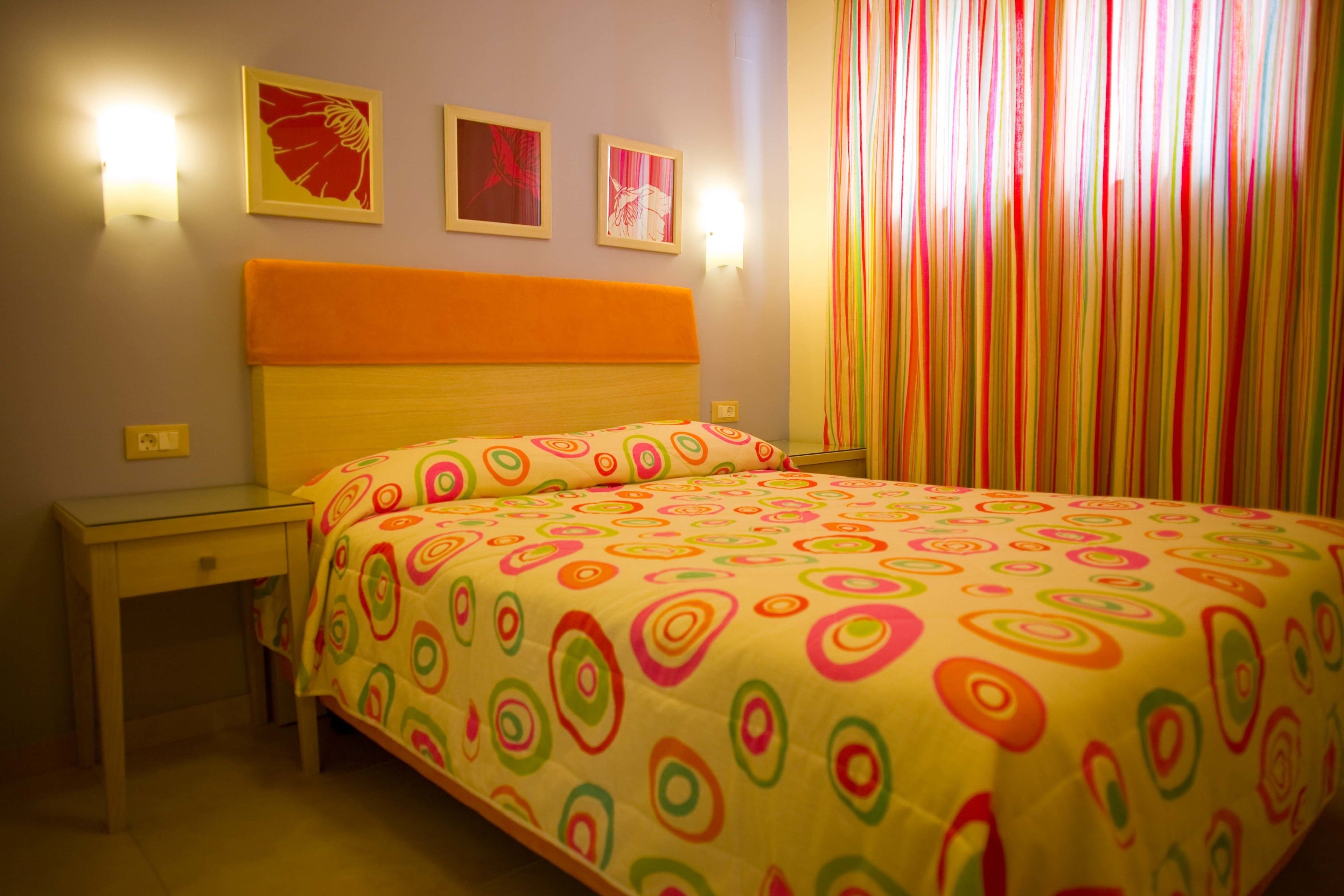 Una camera da letto con un letto, un comodino, una lampada e una finestra con tende.
