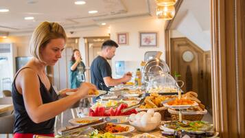 A buffet with various food items and a person serving themselves.