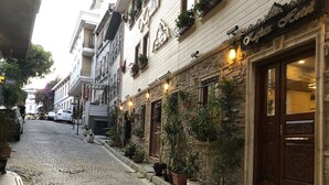 A cobblestone street lined with buildings, including a hotel with a stone facade and potted plants. - Kaftan Hotel (Istanbul)
