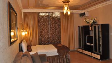 A hotel room with a bed, a sofa, a television, and a cabinet.
