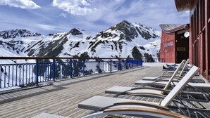 Une terrasse avec des chaises longues donnant sur des montagnes enneigées.