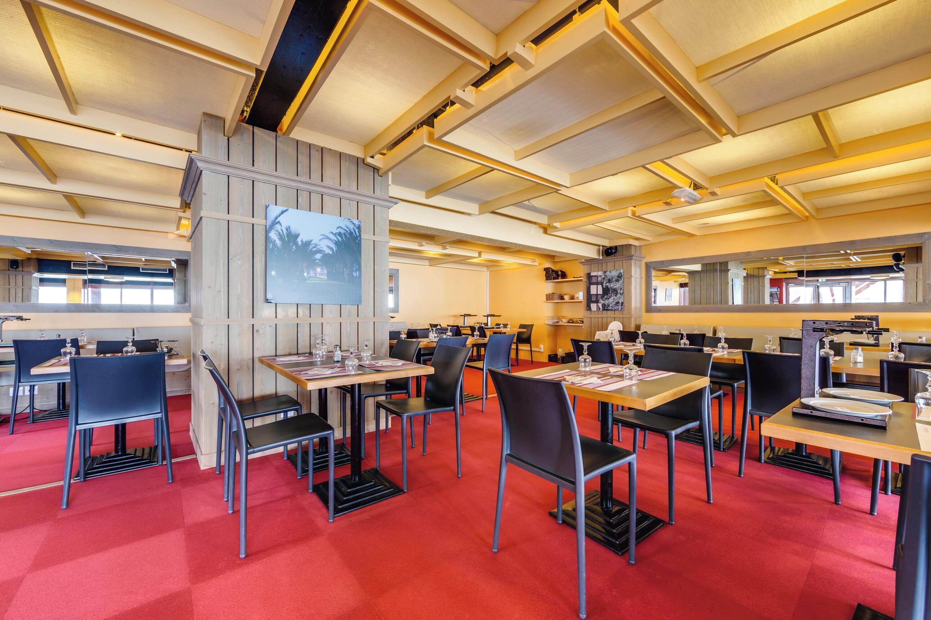 A modern conference room with multiple tables and chairs, a large screen, and a wooden accent wall.