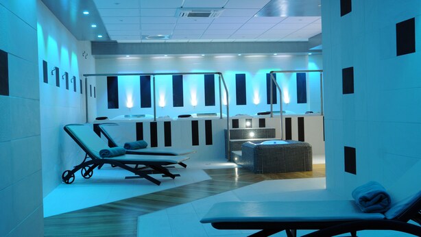 Un espace spa moderne comprenant des chaises longues, une table de massage et un jacuzzi.