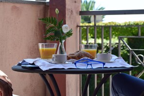 A table with a croissant, two cups of coffee, a glass of orange juice, and a vase with a flower. - Marina Palace Hotel & Congress Hall (Aci Castello)