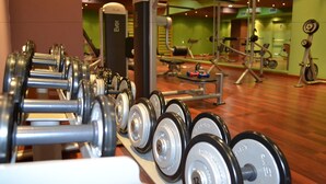 Une salle de sport équipée de divers appareils d’exercice, notamment des haltères et des machines de musculation.