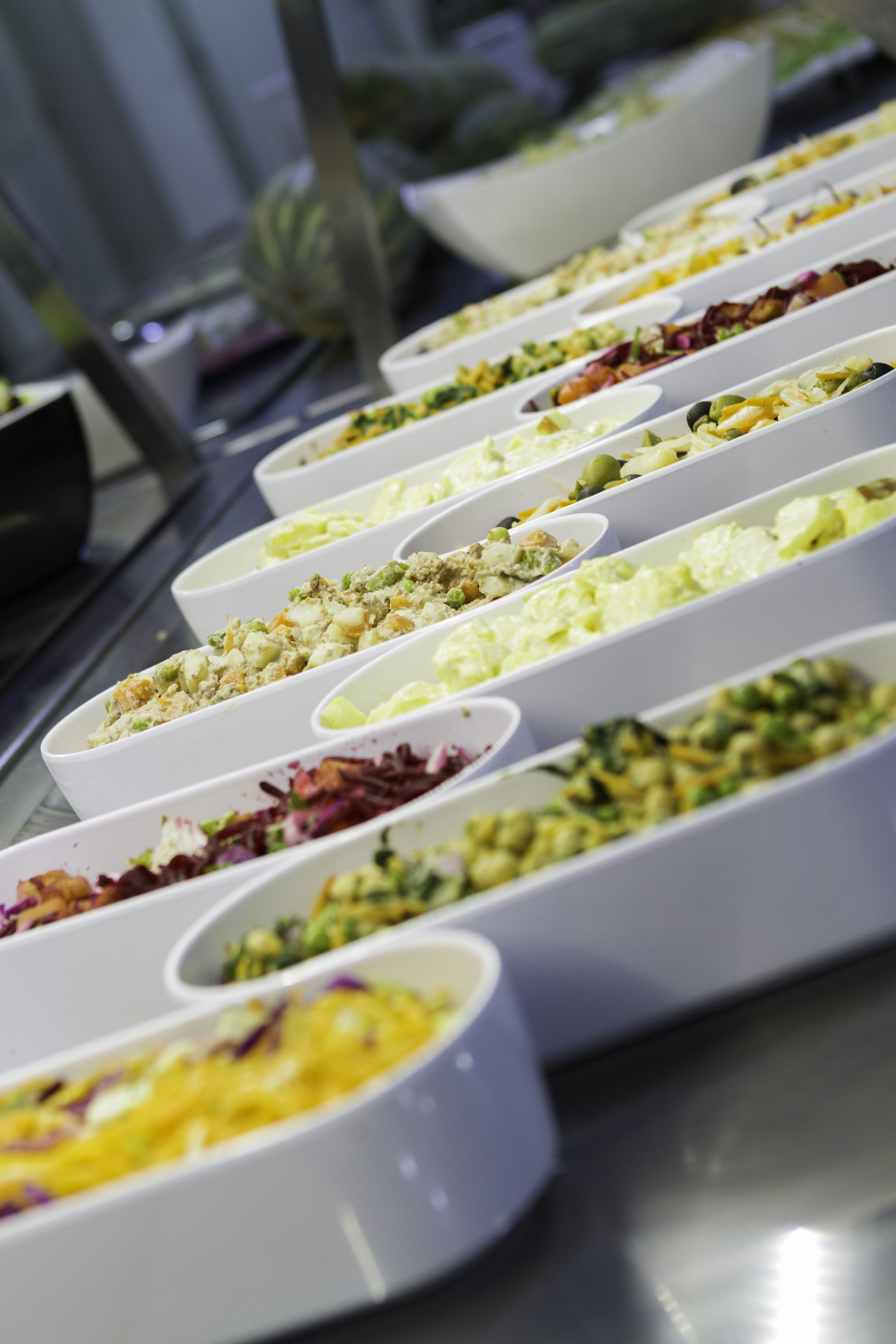 A buffet with various dishes in white bowls.