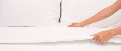 A person adjusting a white mattress on a bed.