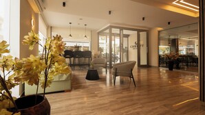 Un intérieur moderne avec un plancher en bois, un coin salon avec des fauteuils et une table, et un mur de verre offrant une vue dégagée.
