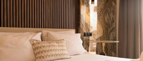 Ein Hotelzimmer mit Bett, Kissen, Nachttisch und Lampe.
