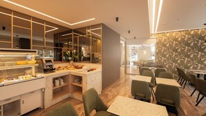 Un restaurant moderne doté d’un buffet, de chaises recouvertes d’un tissu vert et d’un mur orné d’un papier peint à motifs.