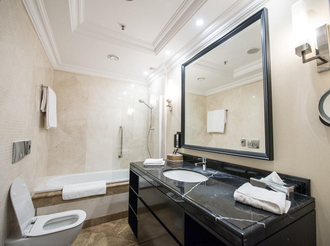 A modern bathroom with a bathtub, two sinks, a large mirror, and a shower.