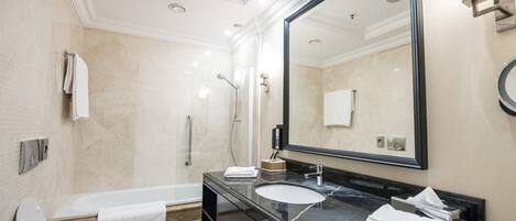 A modern bathroom with a bathtub, two sinks, a large mirror, and a shower.