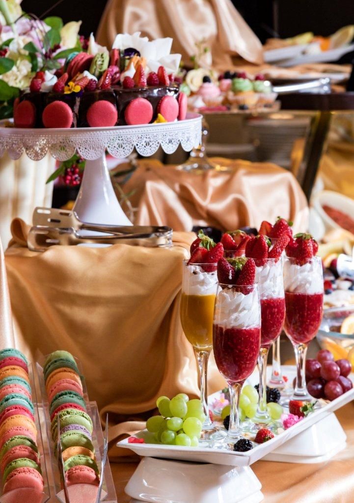 A buffet table with macarons, fruit parfaits, and a variety of desserts.