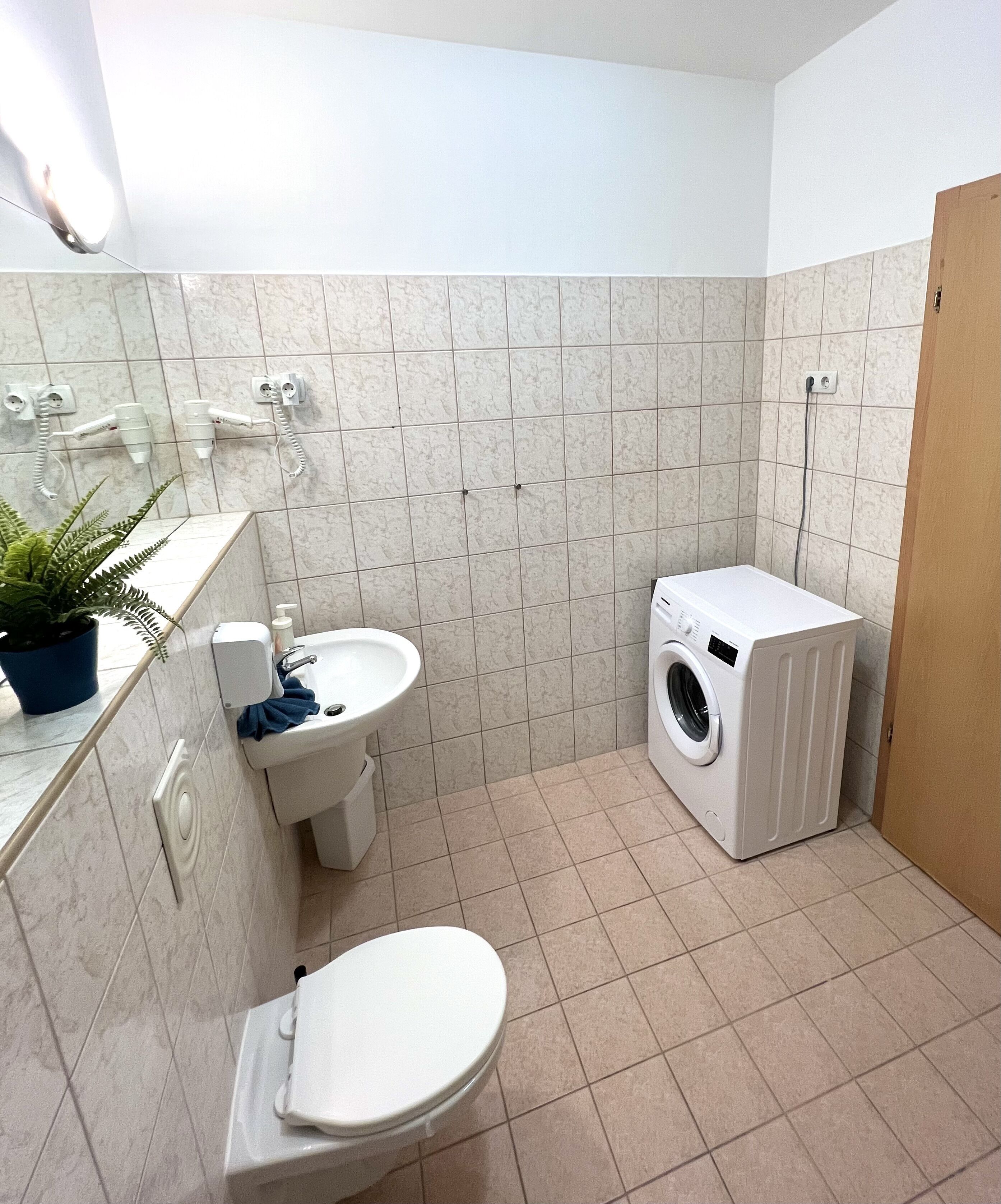 A compact bathroom with a toilet, sink, and washing machine.