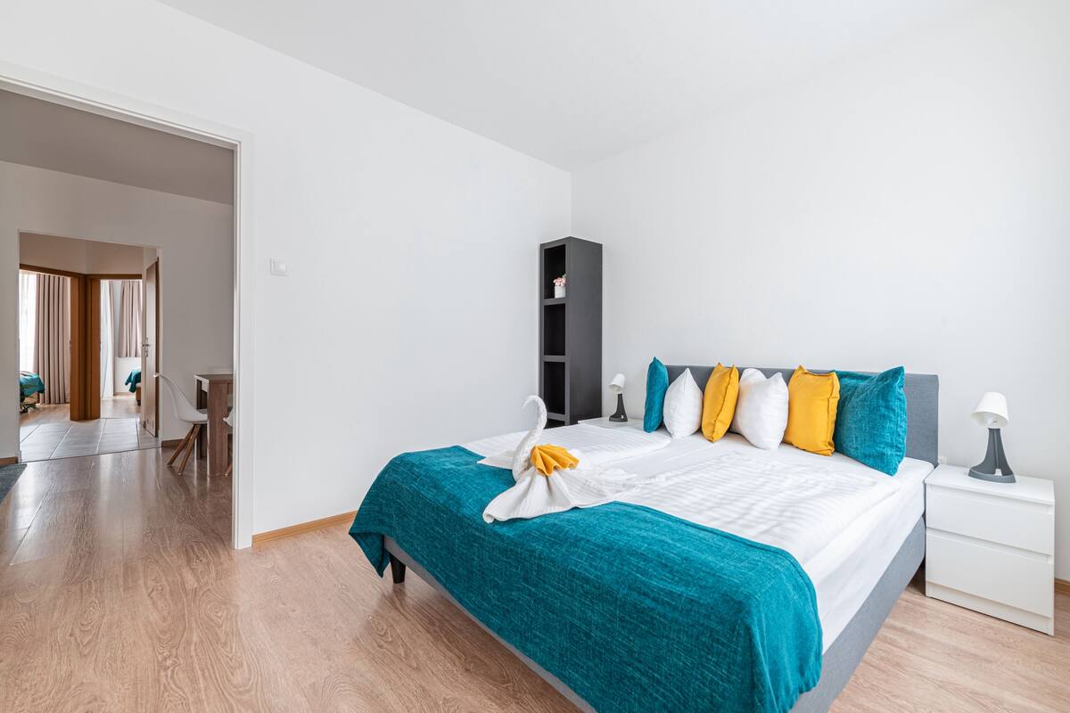 Quarto de hotel moderno com uma cama grande, mesa de cabeceira e guarda-roupa.
