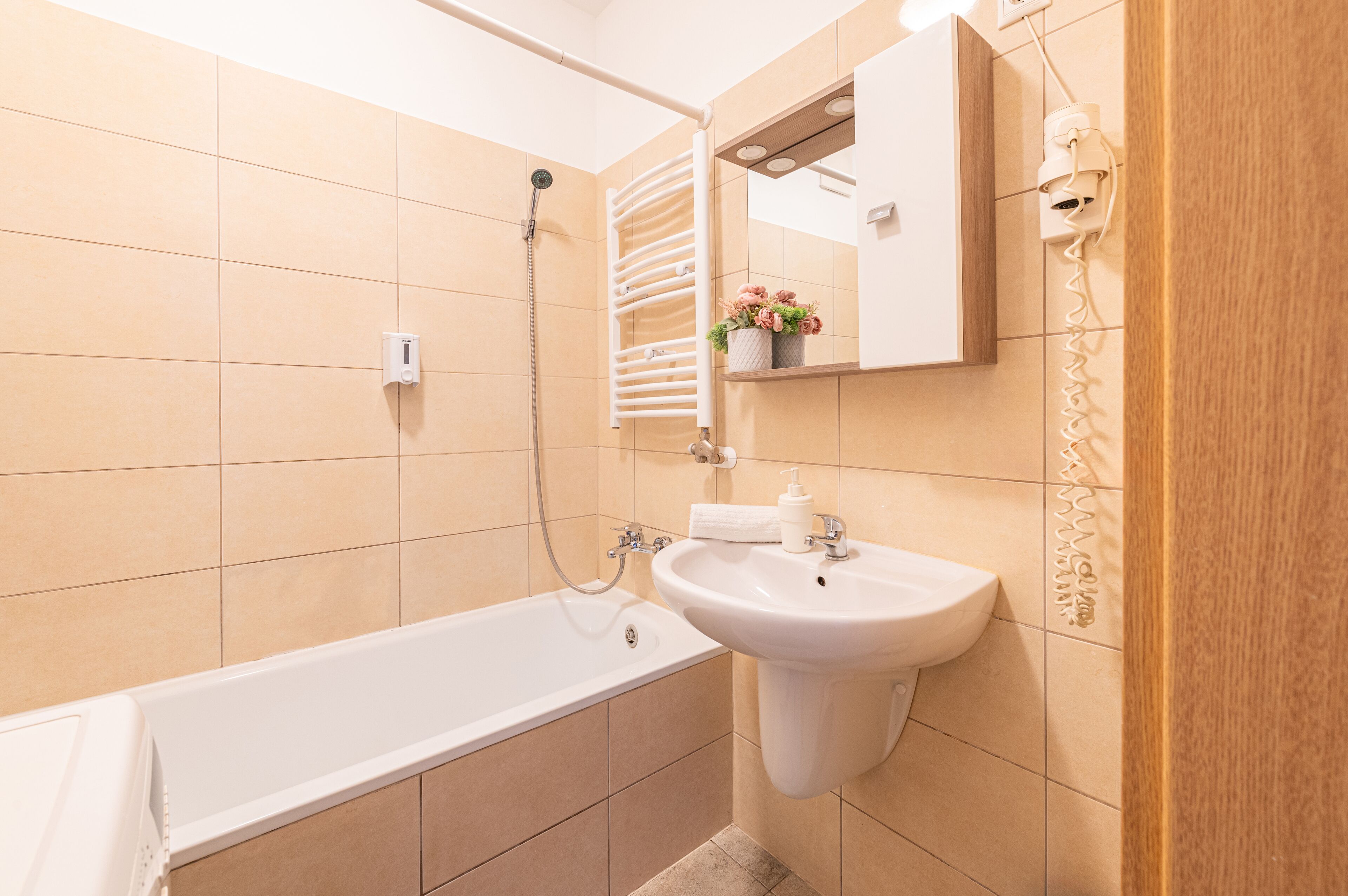 A bathroom with a bathtub, a sink, a mirror, and a towel rack.