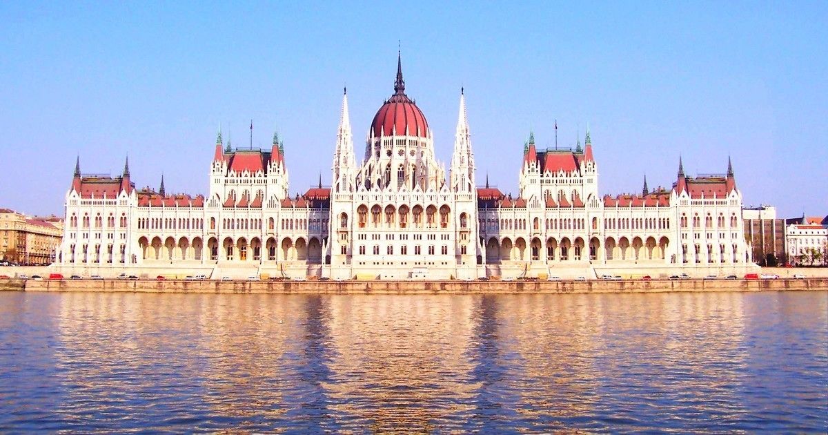 A large, ornate building with a central dome and multiple towers, situated by a body of water.