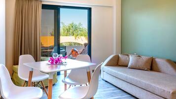 A modern living room with a sofa, a dining table with chairs, and a large window with curtains.